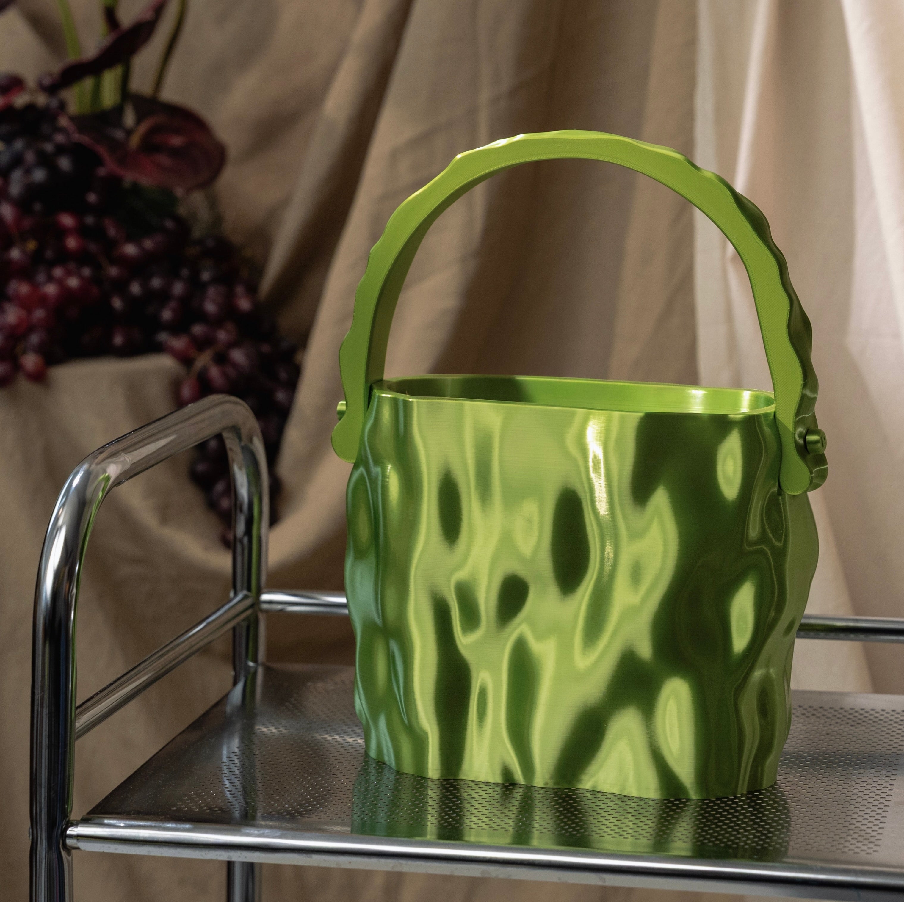 MELT Acid green sculptural handbag placed on a chrome trolley against an ecru draped backdrop.