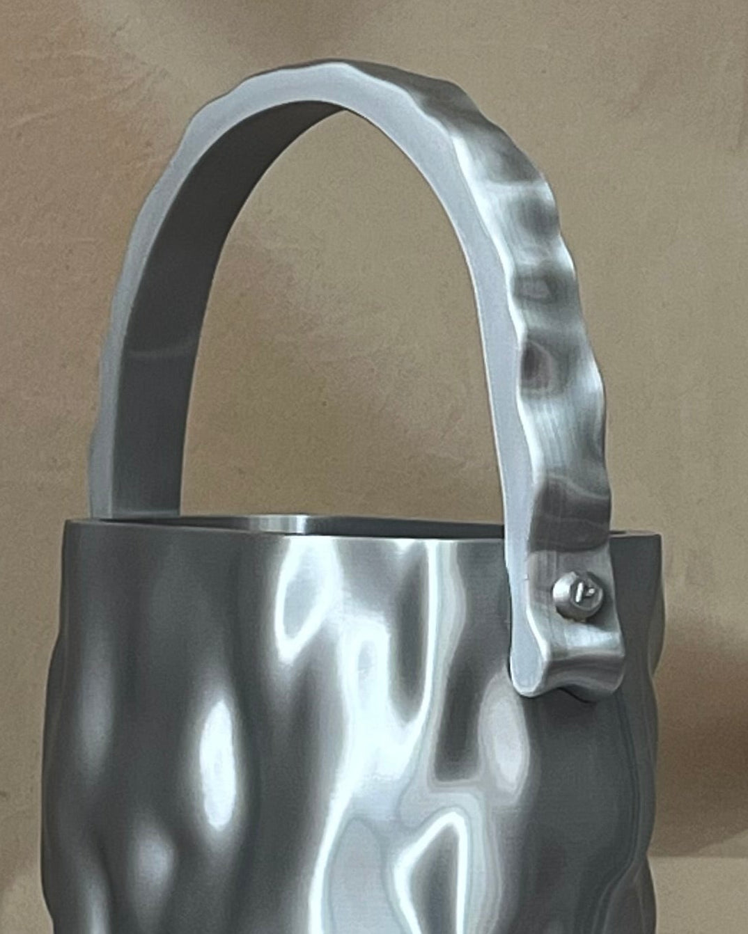 Close-up of MELT bag in Molten Silver, showing the sculptural handle, metallic surface and visible side attachment detail.